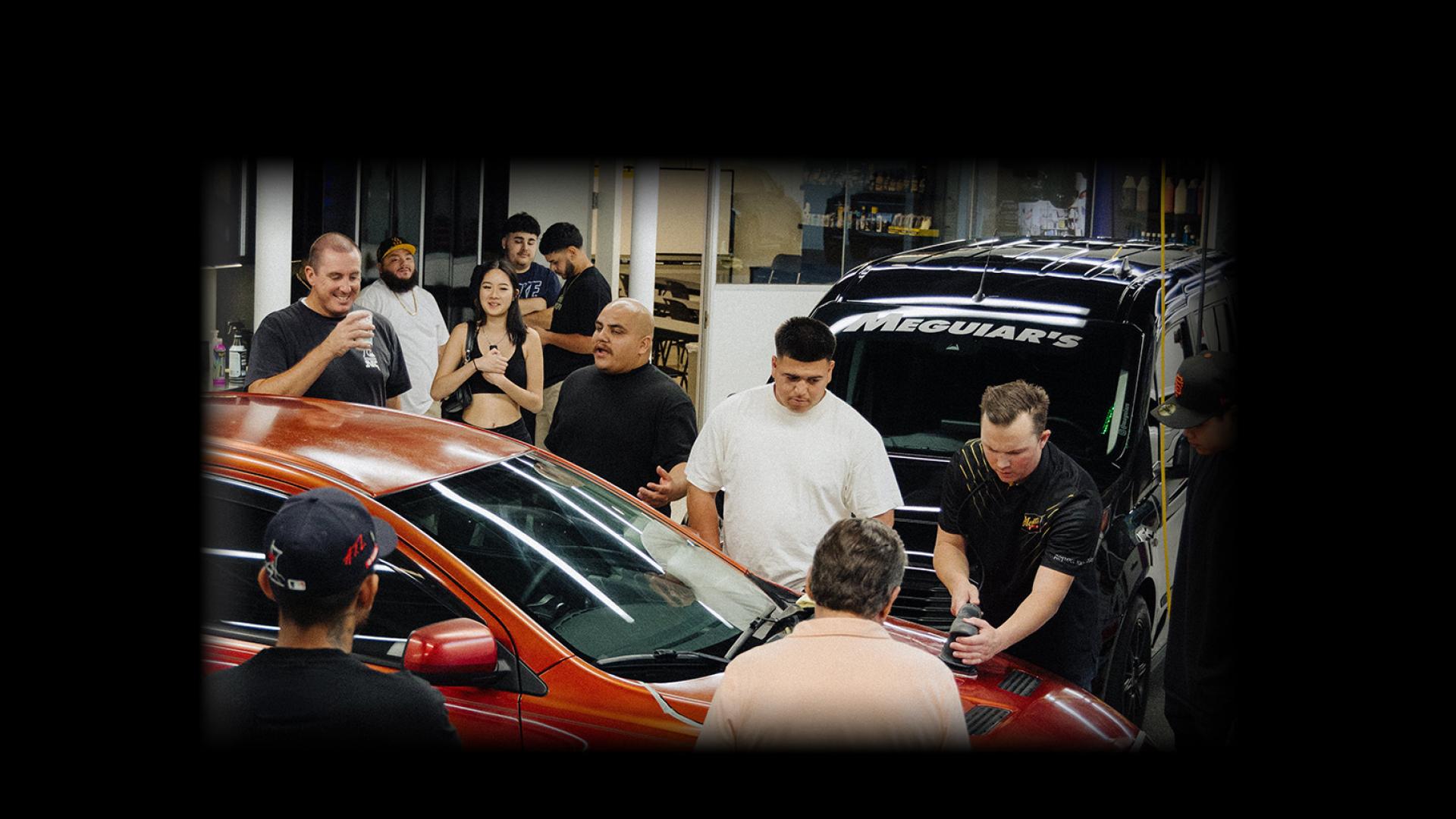 People standing around looking at a red car
