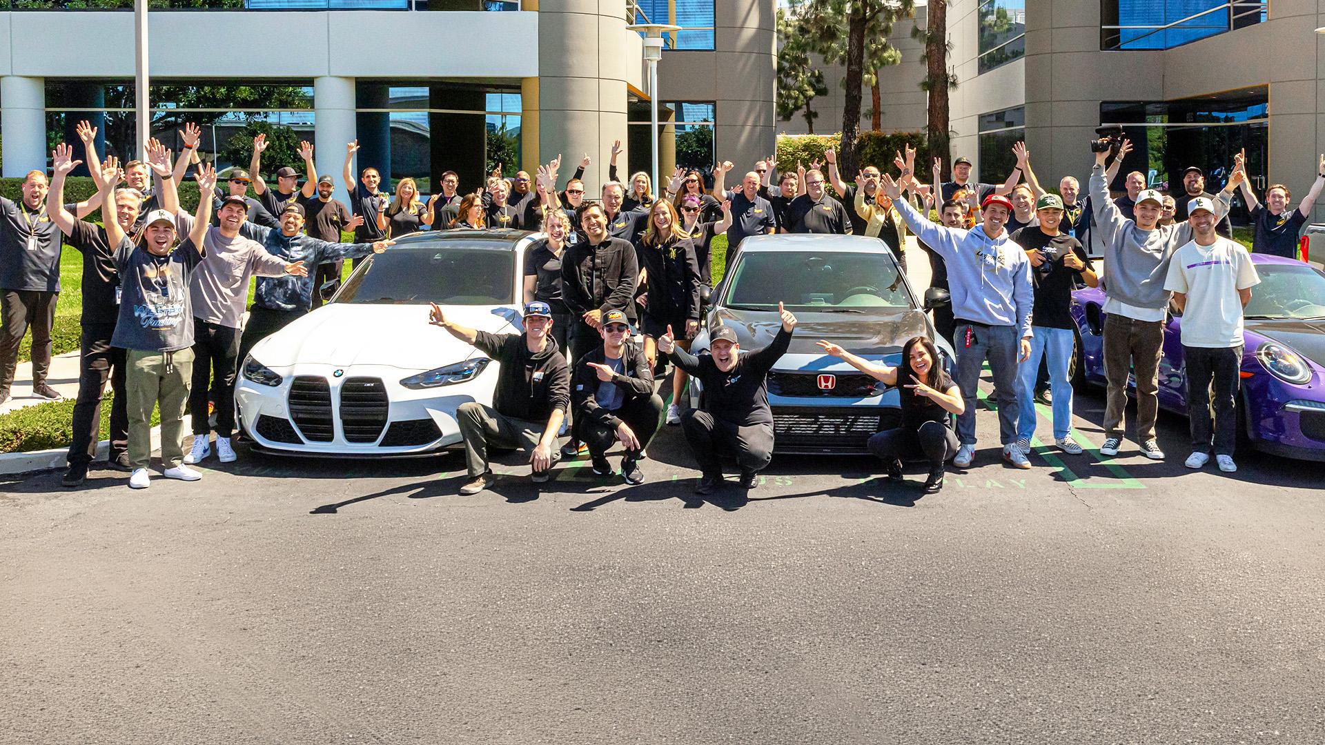 Group of people cheering around cars