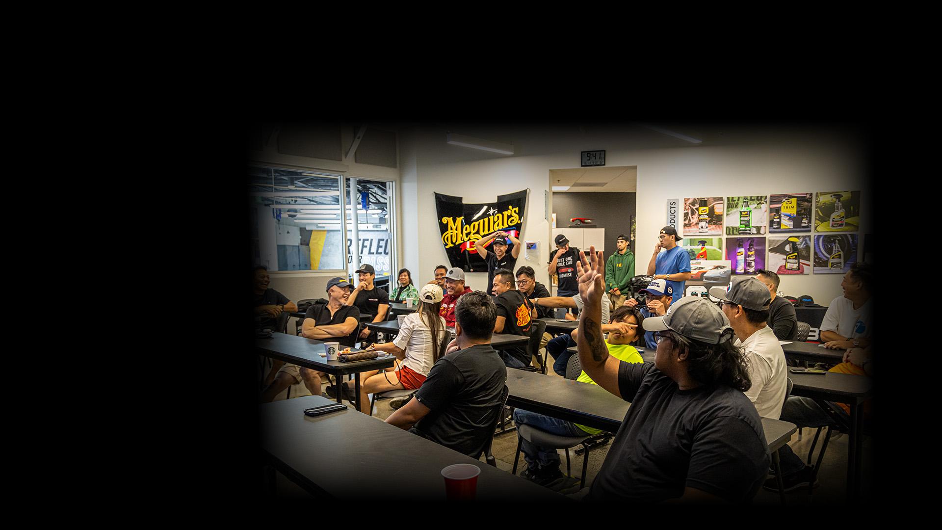 People sitting at desks in an automotive detailing training room