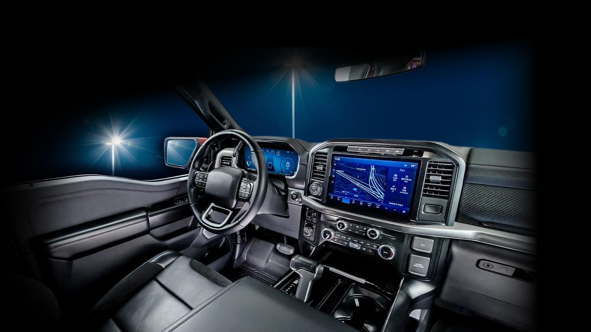 A modern vehicle interior showcasing a black leather driver's seat, steering wheel, and dashboard illuminated by streetlights at night. Features include a large digital touchscreen display with navigation, various control buttons, and a sleek, ergonomic design emphasizing comfort and technology.