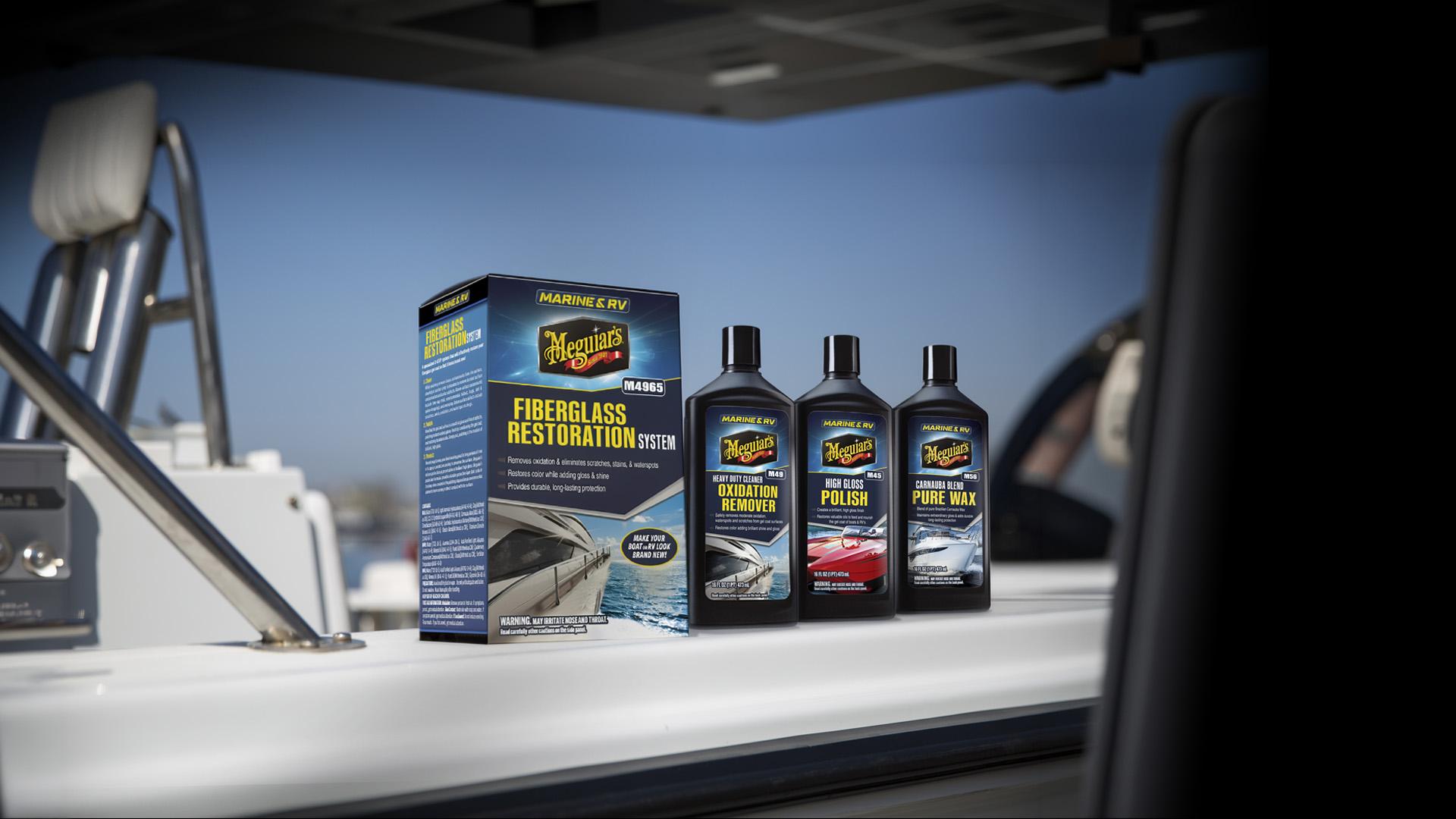 black bottles labeled Oxidation Remover, Polish, and Pure Wax. The image highlights product packaging and branding against a clear sky and boat equipment background, emphasizing marine fiberglass care.