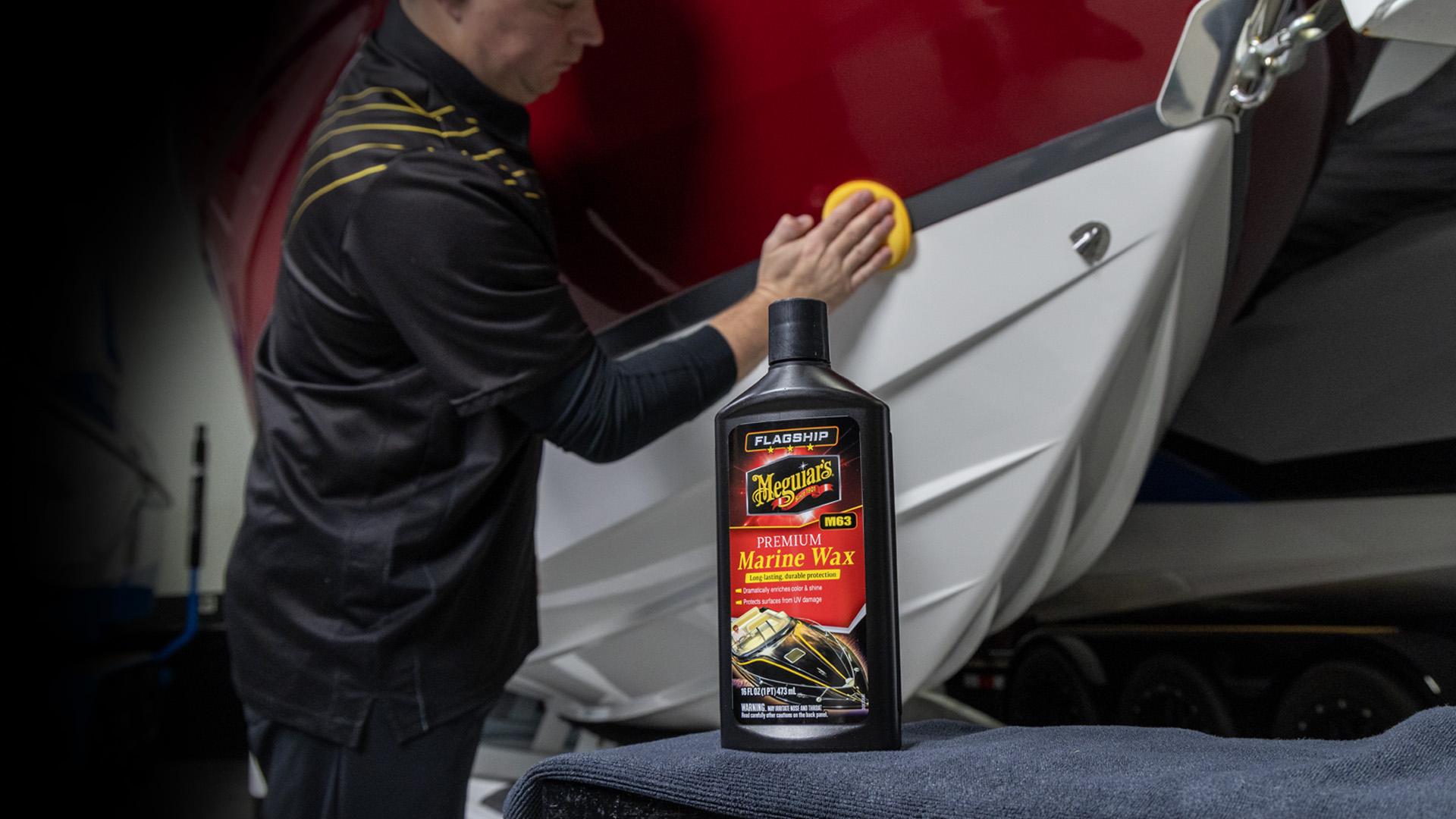 inside a storage or maintenance facility. A bottle of Meguiar's Premium Marine Wax is prominently placed on a blue towel in the foreground, emphasizing boat care and maintenance.