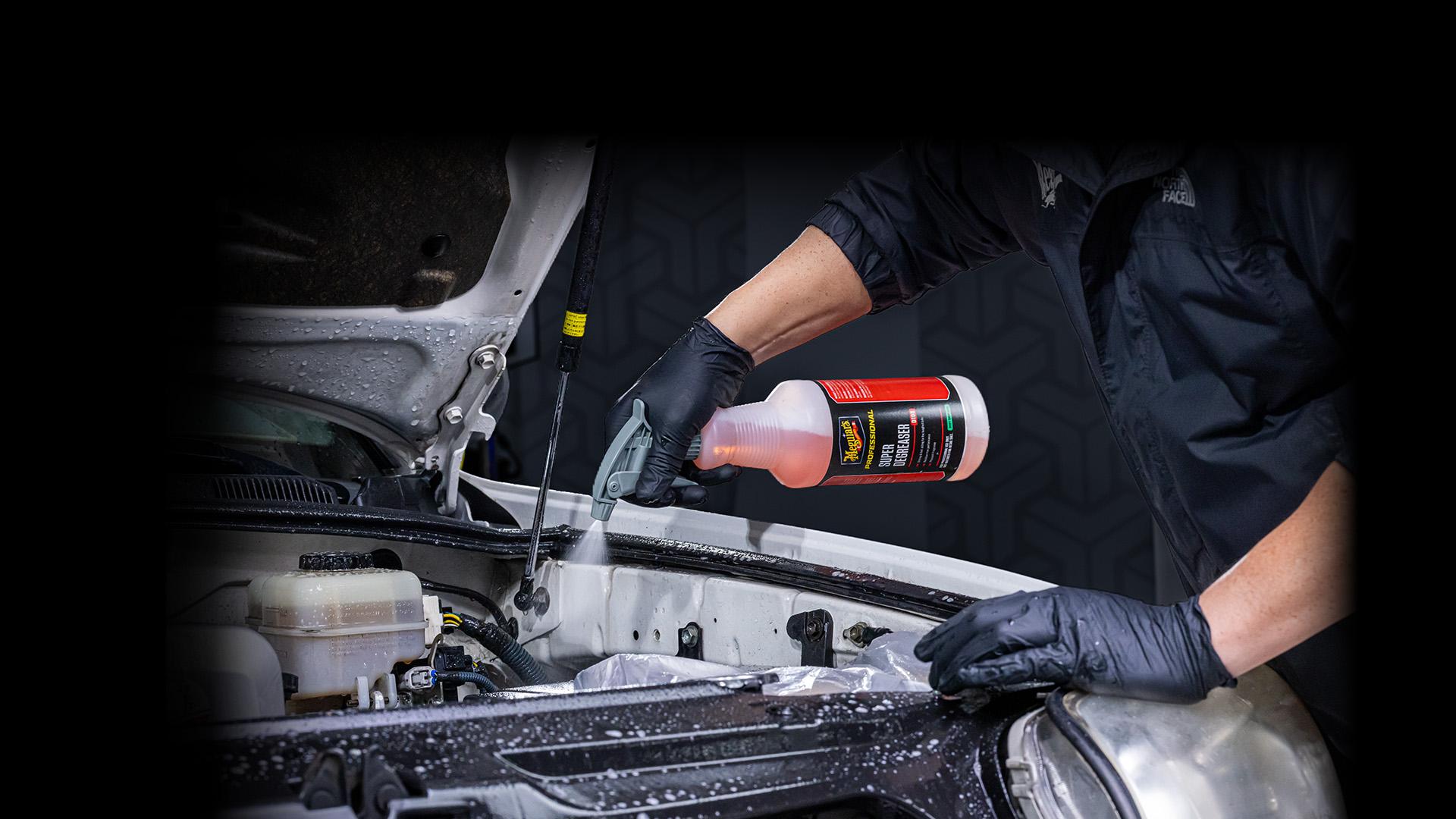 Spraying cleaning product on the engine of a car