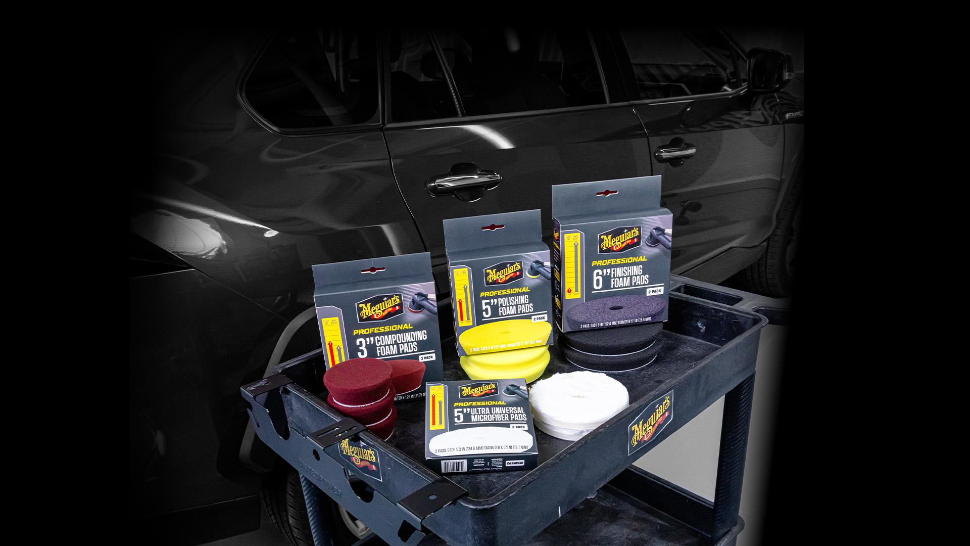 Three boxes of foam pads and a box of microfiber pads sitting out on the top shelf of a detailing cart