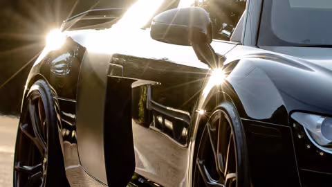 A black sports car with the sun glinting off the front and rear fenders