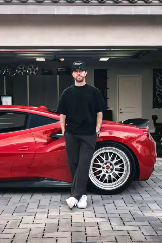 TJ Hunt leaning against a red sports car