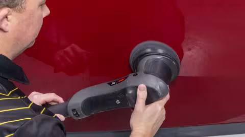 Person using a DA buffer on the side of a boat