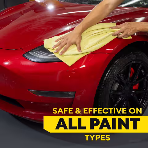 Close-up of a red Tesla being dried with a yellow microfiber towel. The paint appears glossy and reflective. Large text reads “SAFE & EFFECTIVE ON ALL PAINT TYPES.” The image emphasizes compatibility with a variety of automotive paint finishes.